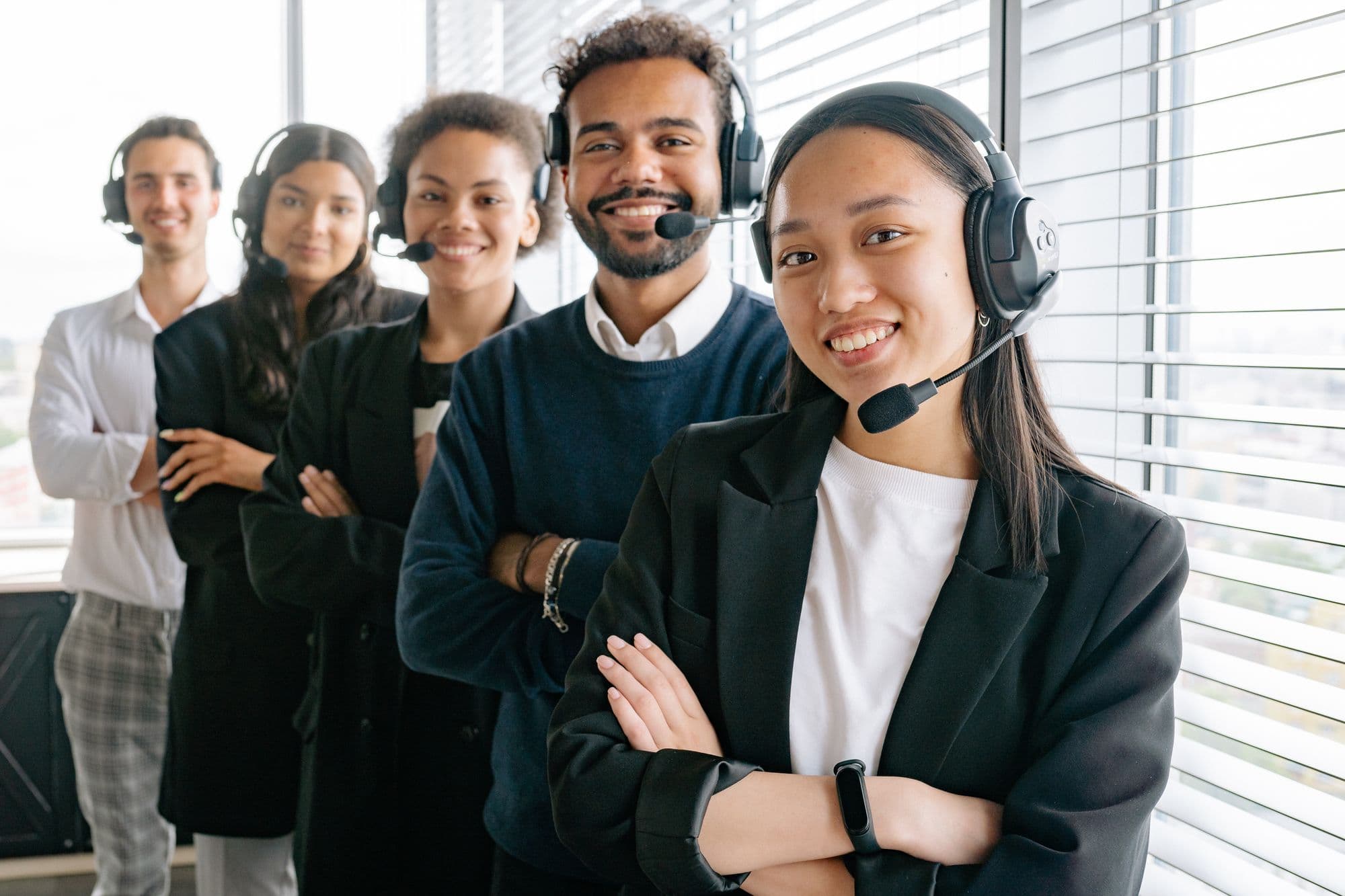 A group of support agents in headsets standing together in an office